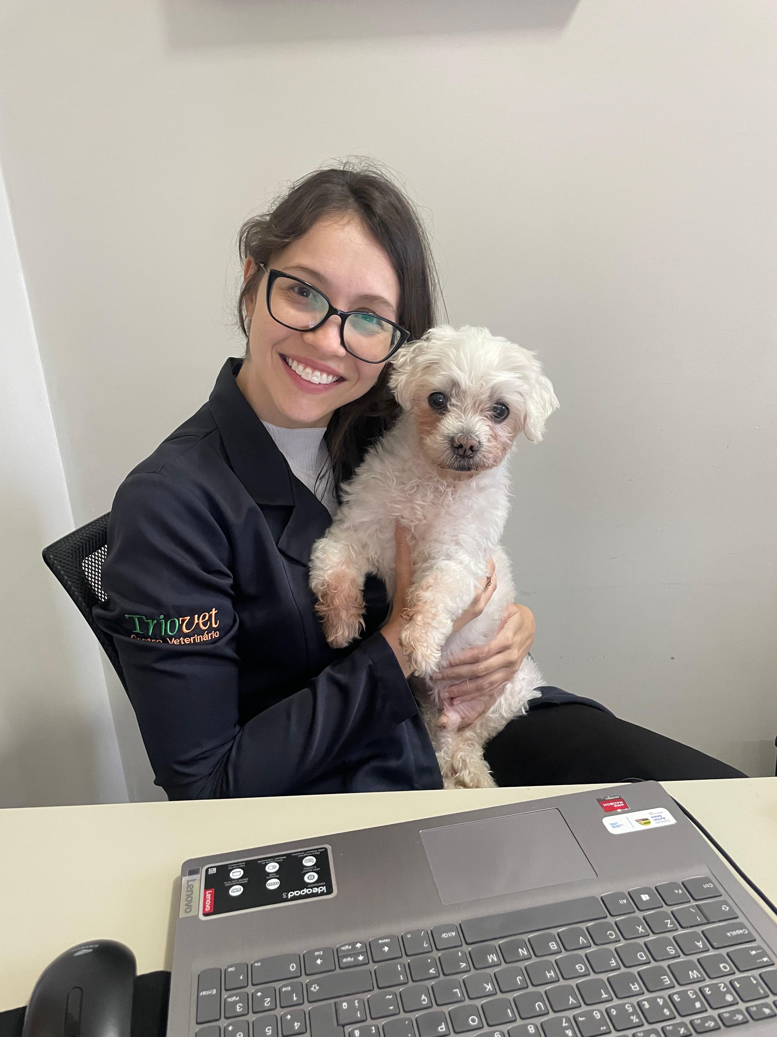 Dra. Paula sorrindo ao lado de um cão no consultório